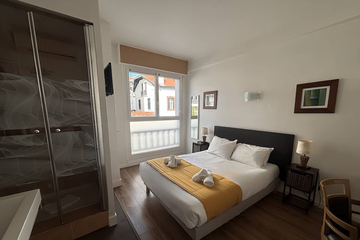A bedroom with a bed, a nightstand, a chair, a window, and a door.