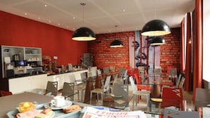 A restaurant with a brick wall, red chairs, and a counter with kitchen equipment.