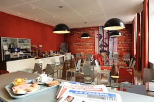 Um restaurante com parede de tijolos, cadeiras vermelhas e balcão com equipamentos de cozinha.