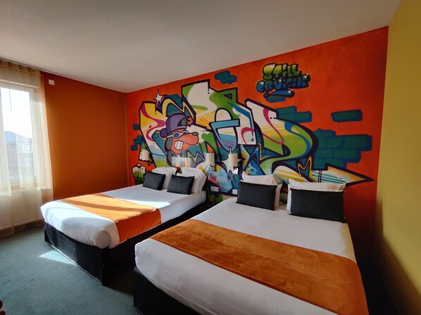 Une chambre d’hôtel avec deux lits, un mur décoré de graffitis colorés et une fenêtre avec des rideaux.