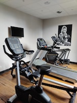 Un gimnasio con bicicletas estáticas, cintas de correr y un banco para pesas.