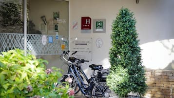 A building entrance with a sign for 'LE RICHEBOURG' and a 'Thalgo' sign, a small tree, and two bicycles parked outside.