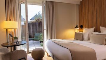 Habitación de hotel con cama, mesitas de noche, lámpara, silla y vistas al exterior.