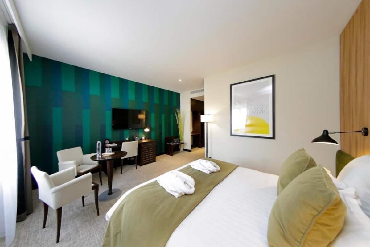Ein Hotelzimmer mit Bett, Schreibtisch, Stuhl und Fernseher.
