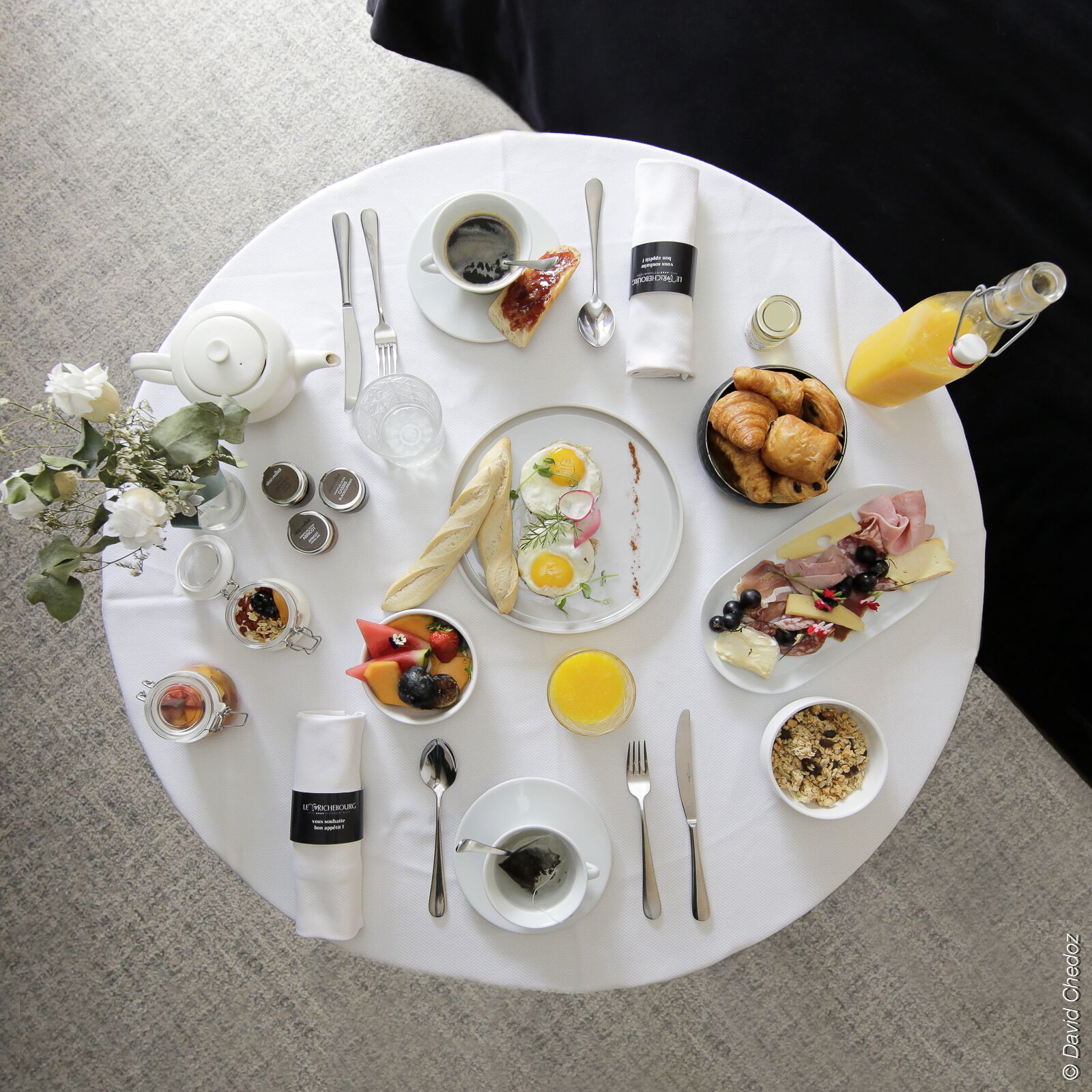 A breakfast setting with various dishes, utensils, and condiments on a round table.