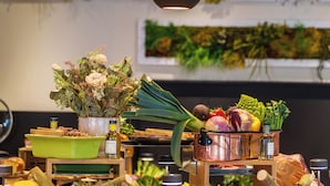 A kitchen area with a green bowl, a bottle, and various vegetables on the counter.