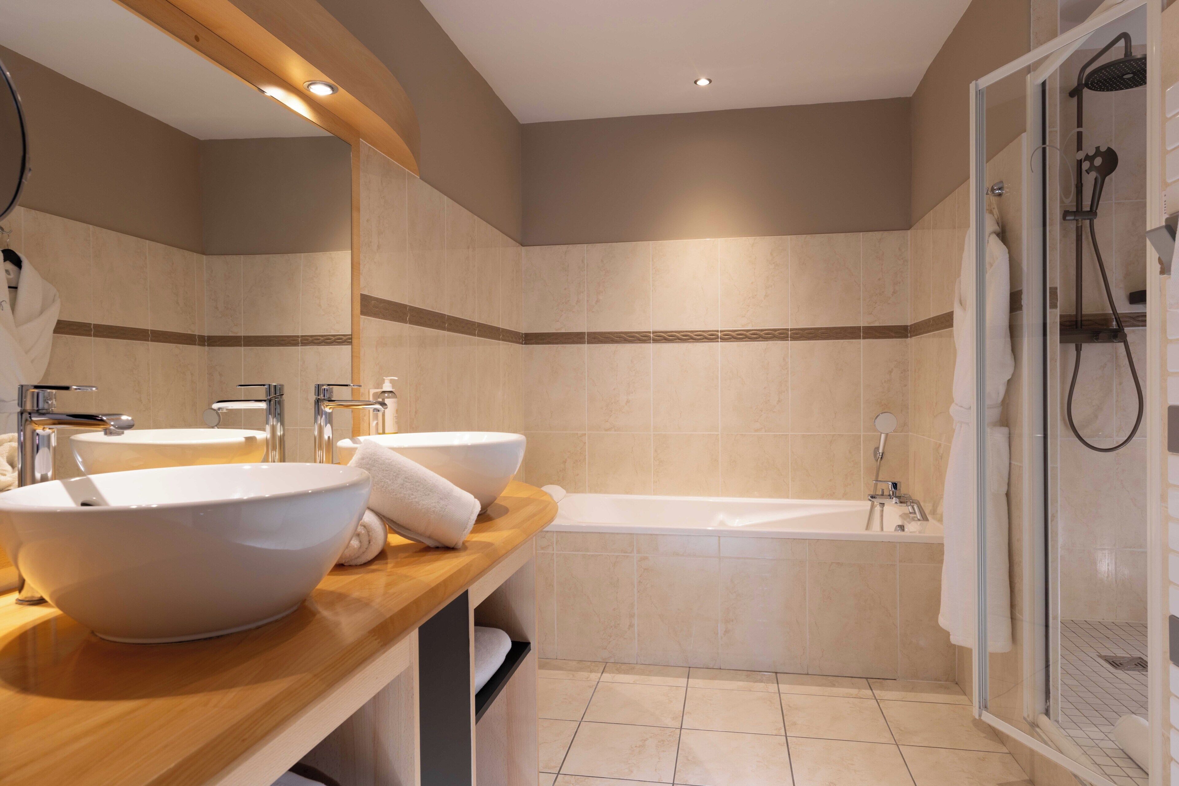 A modern bathroom with two sinks, a bathtub, and a shower.