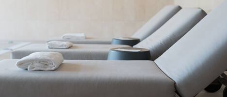 A spa area with massage chairs, towels, and a clock on the wall.