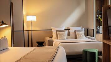 Ein Hotelzimmer mit zwei Betten, einer Stehlampe, einem grünen Hocker und einem Fernseher.