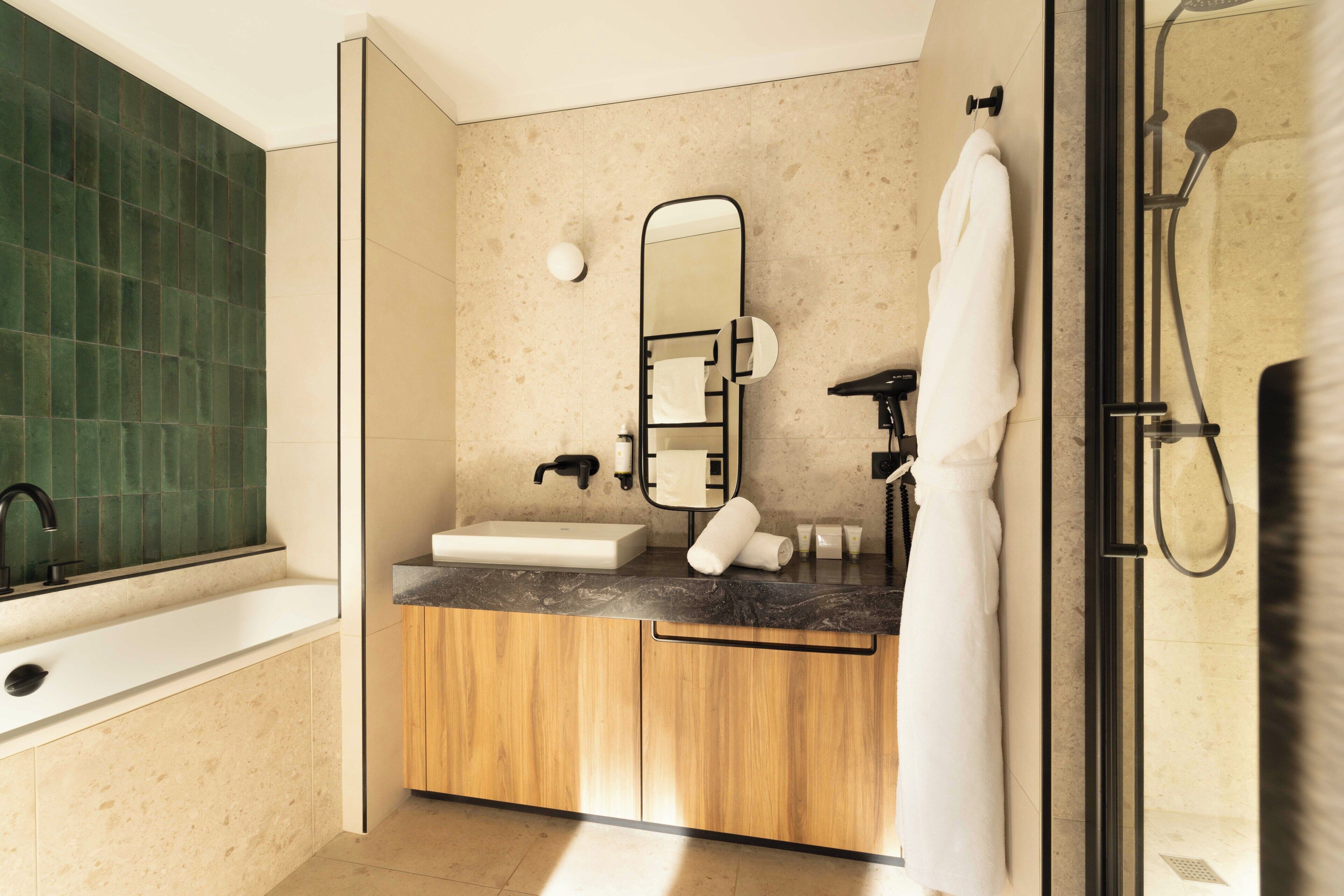 Une salle de bain moderne équipée d’une baignoire, d’un lavabo, d’un miroir et d’un espace douche.