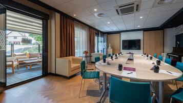 A conference room with a large table, chairs, and a television screen.