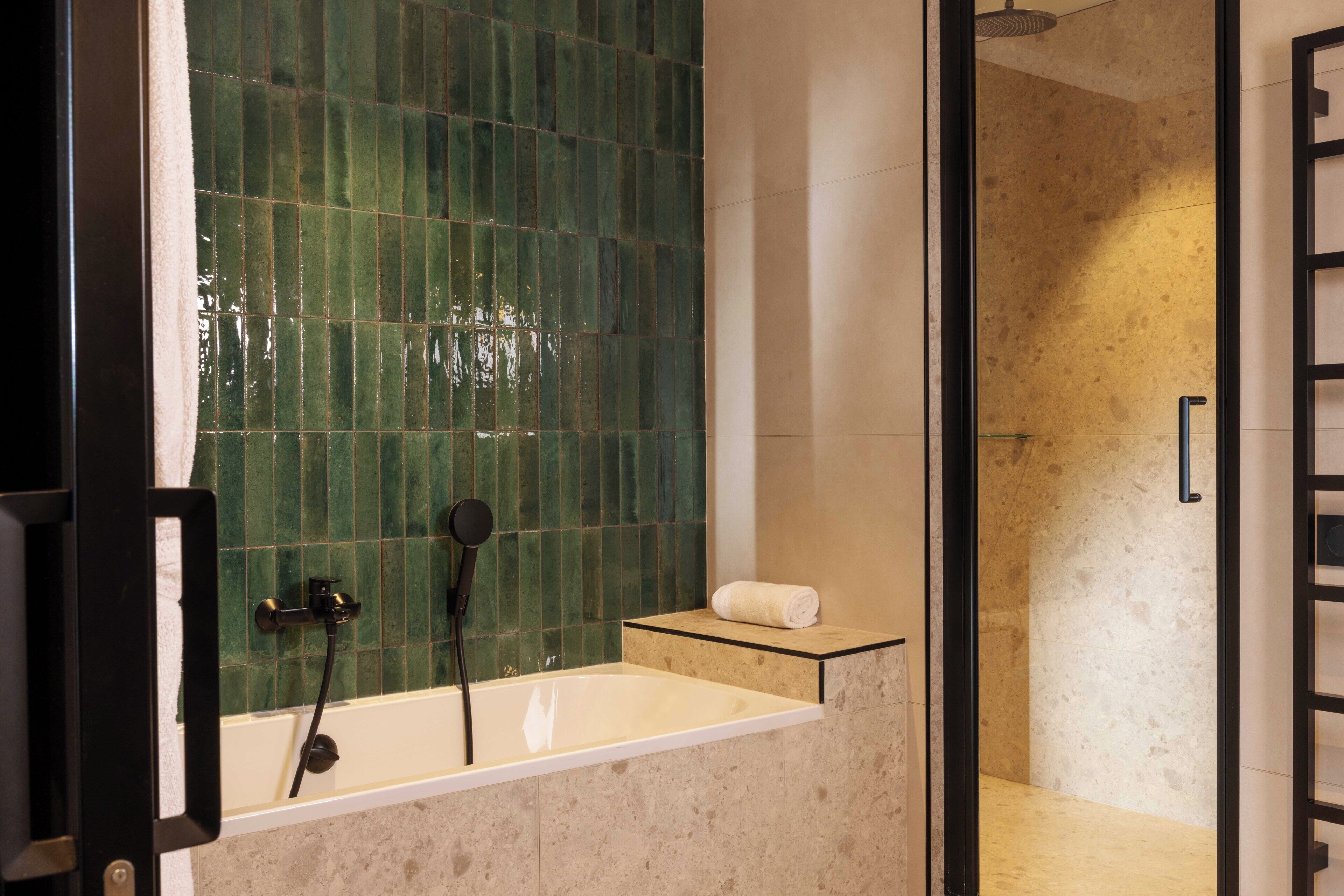 A bathroom with a bathtub, a shower, and a towel on a shelf.