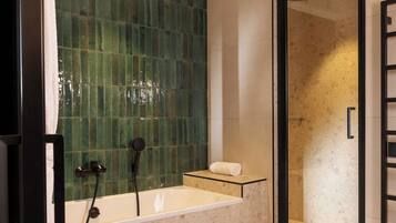 A bathroom with a bathtub, a shower, and a towel on a shelf.