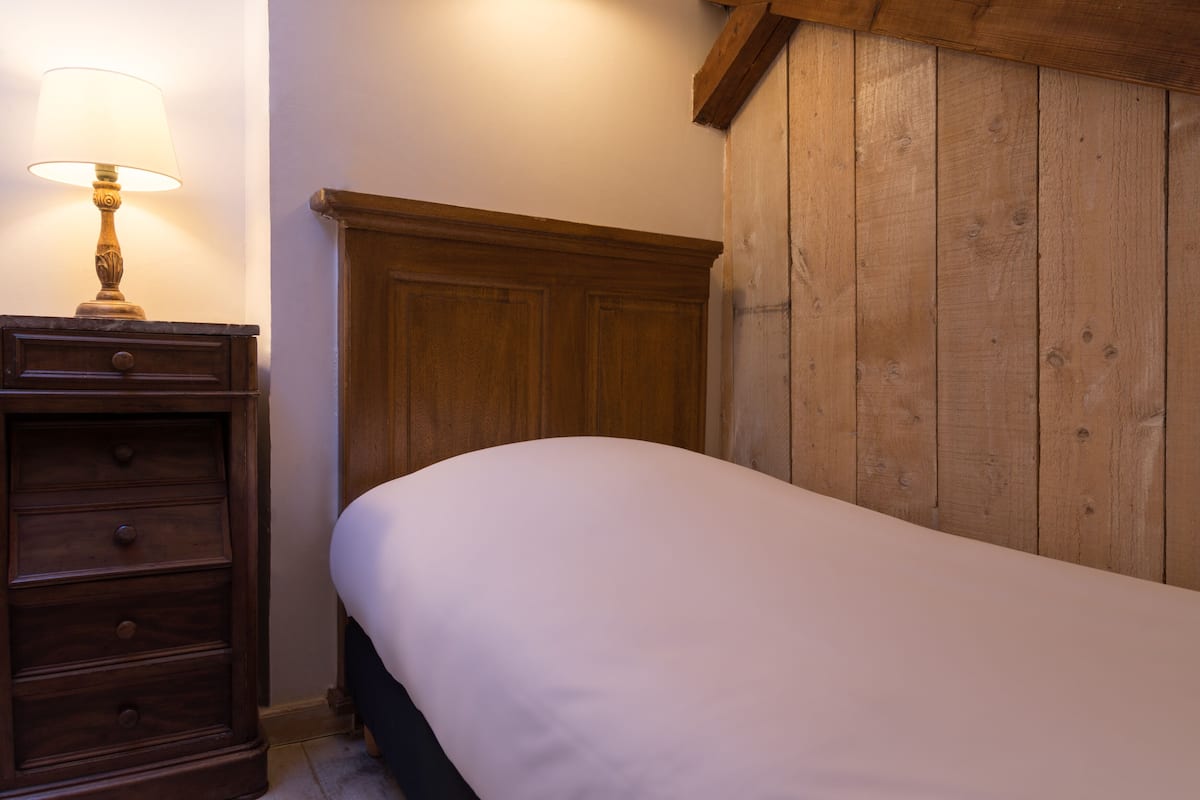Une chambre à coucher avec une tête de lit en bois, une table de chevet avec une lampe et une commode avec des tiroirs.
