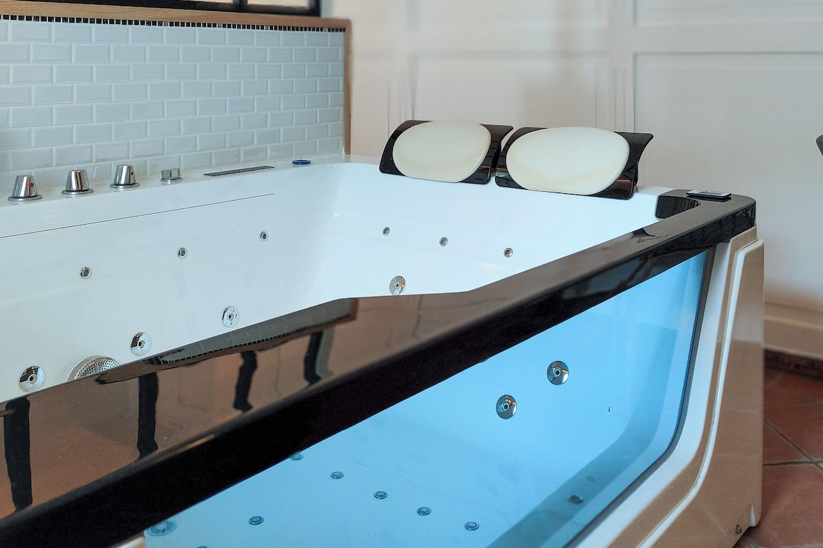 Une salle de bain moderne avec une baignoire sur pieds, un miroir et un mur recouvert de carreaux.