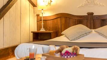 Una camera d'albergo accogliente con una testiera in legno, un comodino con una lampada e un vassoio con prodotti per la colazione.