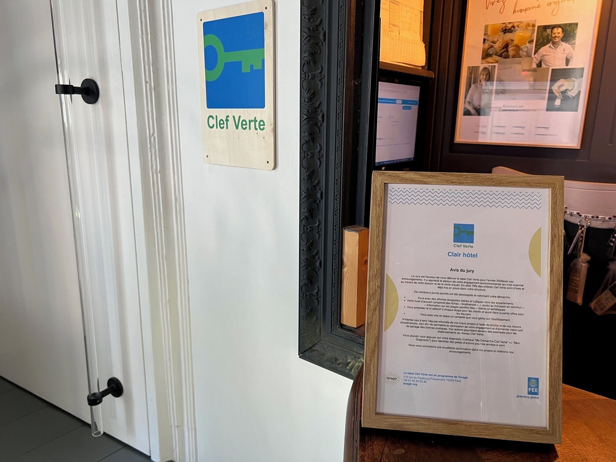 Una puerta con un letrero que dice 'Clef Verte' y un documento enmarcado sobre una mesa.
