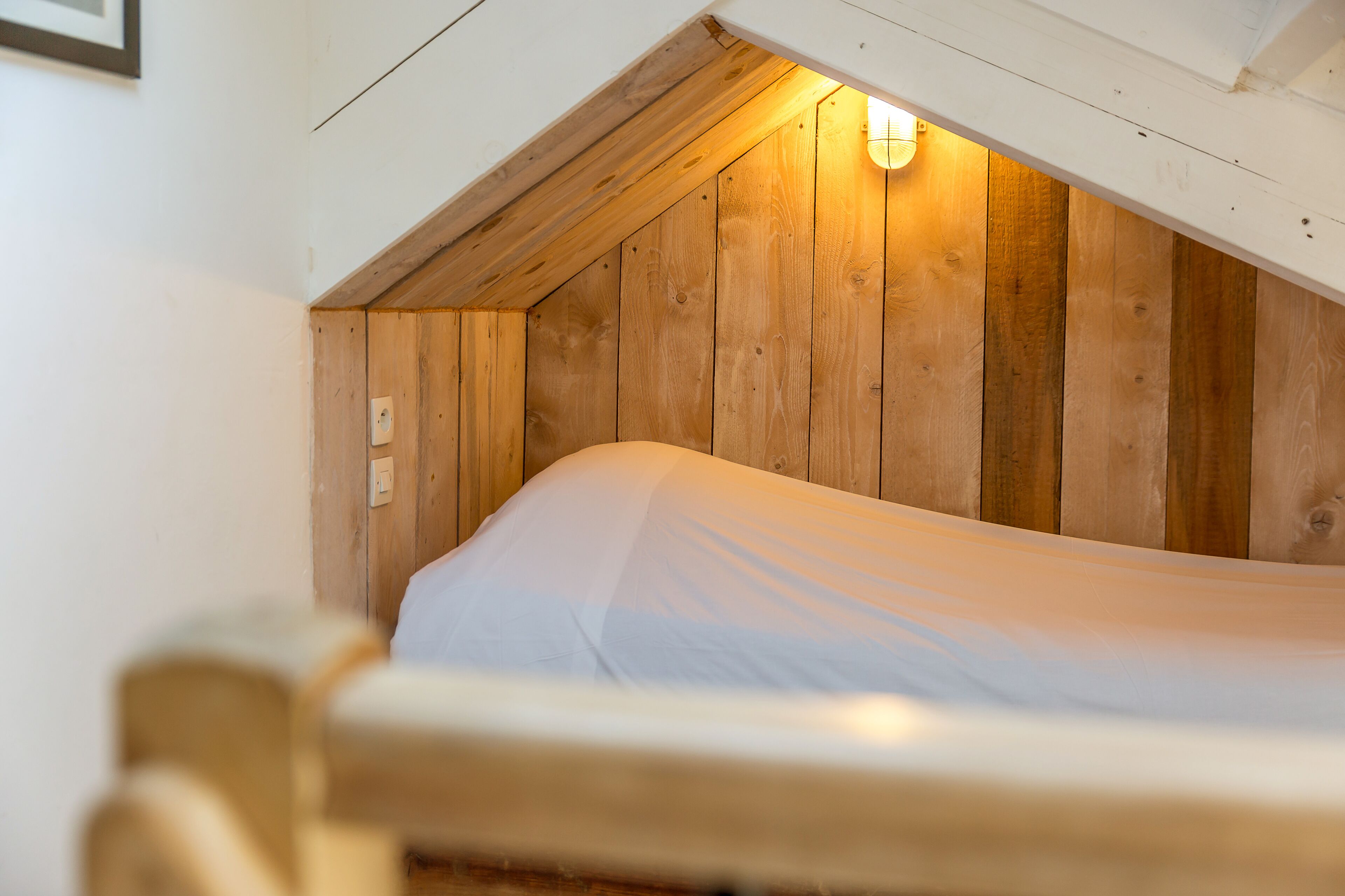 A single bed in a room with wooden walls and a sloped ceiling.