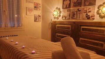 A room with a bed, a wall decorated with various framed pictures, and a wooden headboard.