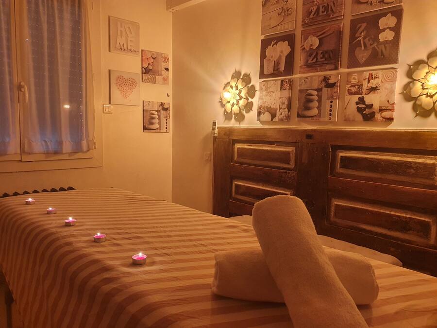 A room with a bed, a wall decorated with various framed pictures, and a wooden headboard.
