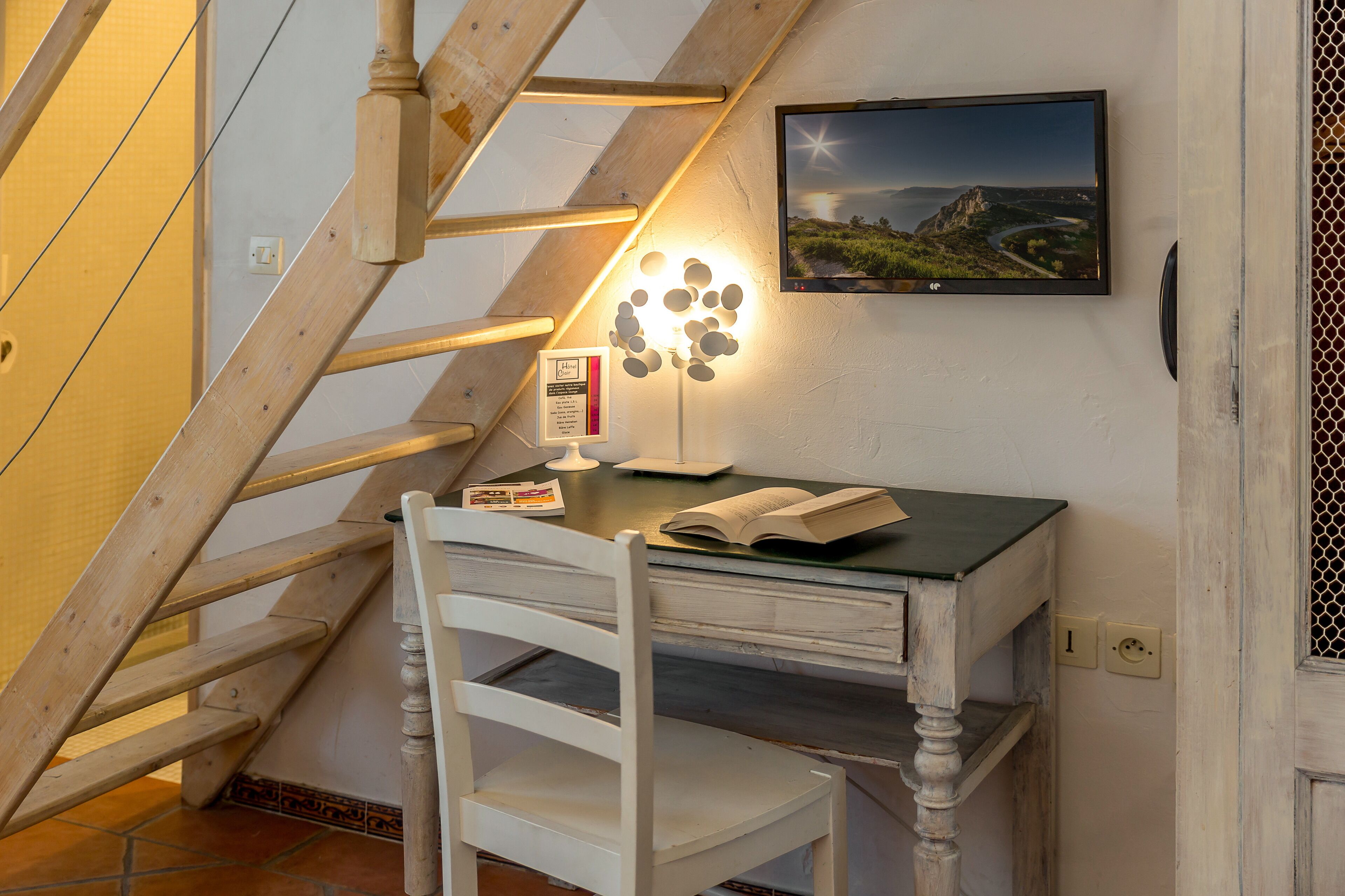 A study area with a wooden desk, a chair, a lamp, and a framed picture on the wall.