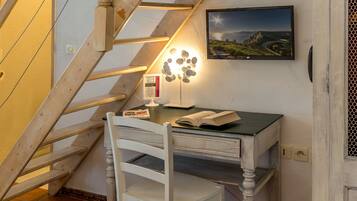 Un espace de travail comprenant un bureau en bois, une chaise, une lampe et un tableau encadré accroché au mur.
