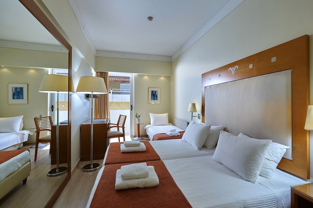A hotel room with two beds, a desk, and a chair.