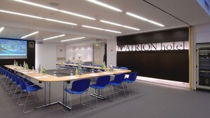 A conference room with a long table, blue chairs, and a projection screen. - Atrion Hotel (Heraklion)