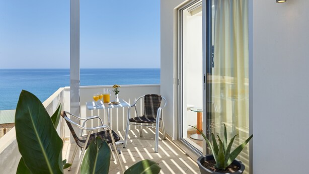 A balcony with a table, chairs, and a potted plant. - Atrion Hotel (Heraklion)