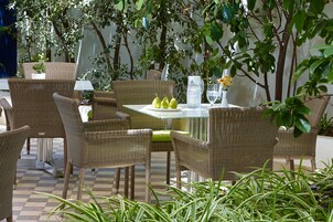 Un espacio de estar al aire libre con muebles de mimbre, una mesa, sillas y una planta en maceta.