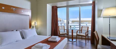 Habitación de hotel con cama, escritorio, silla, mesa y vista al mar.