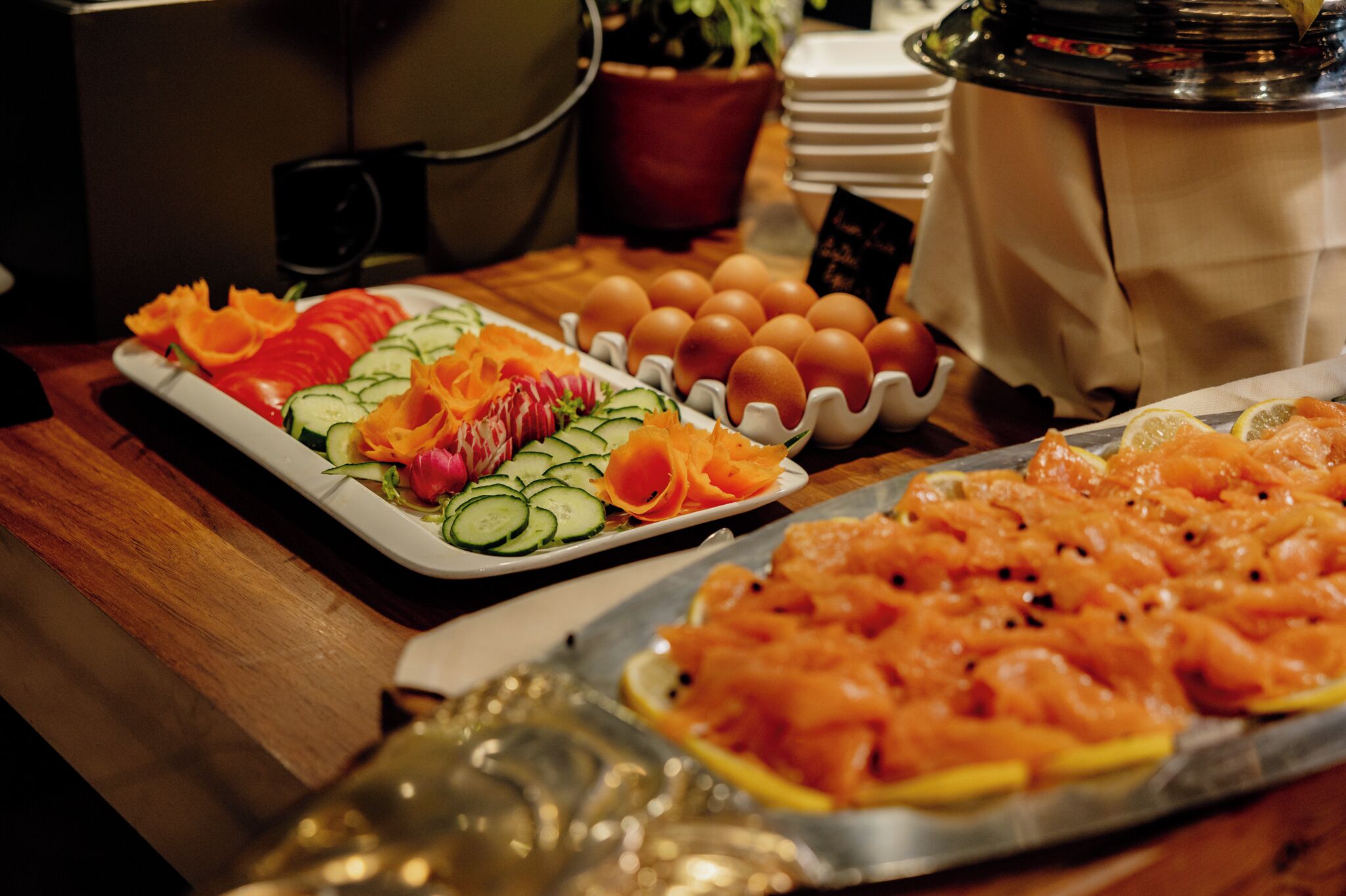 A buffet table with various food items including salmon, eggs, and vegetables.
