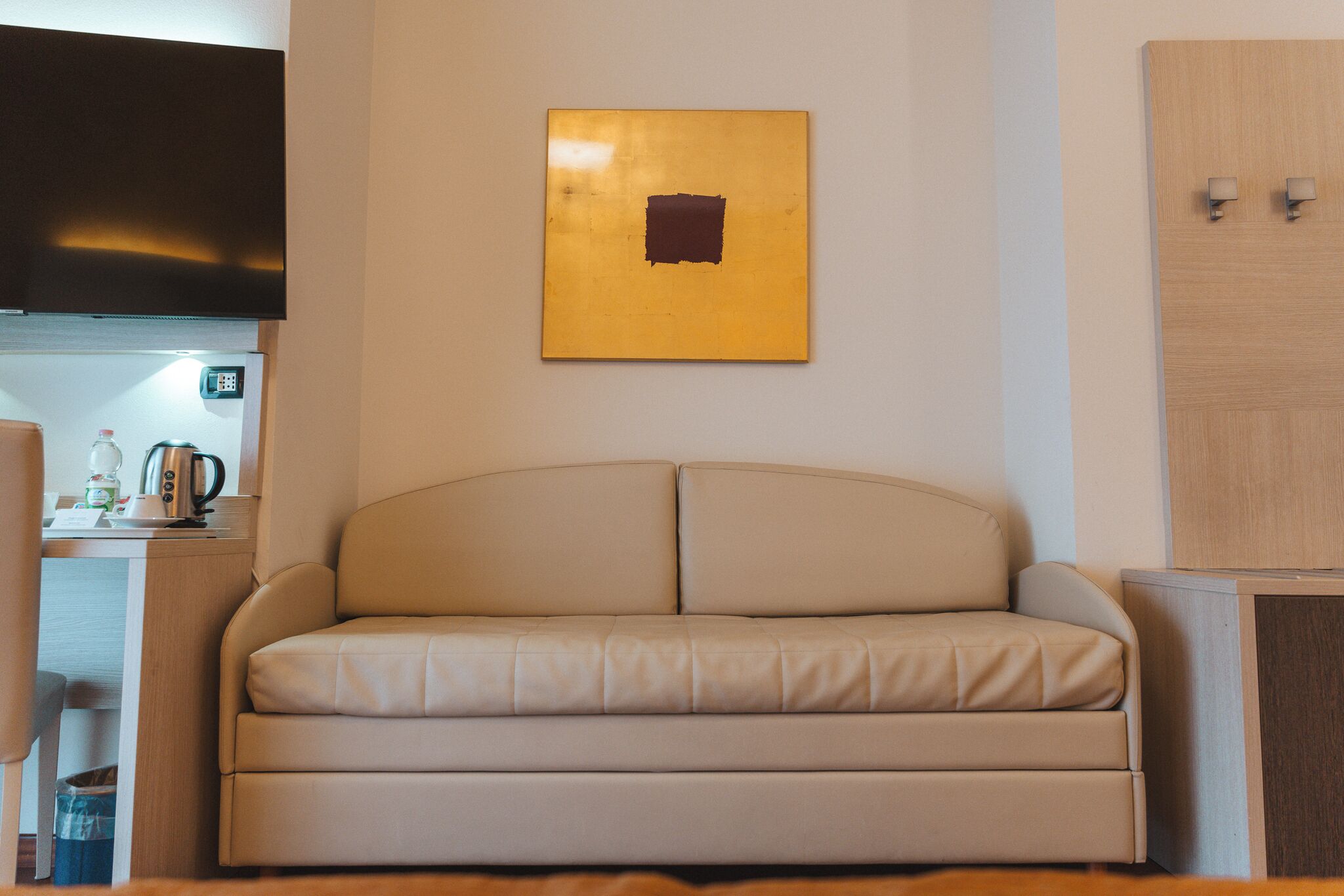 Una sala de estar moderna con un sofá beige, un televisor de pantalla plana montado en la pared y un aparador de madera.