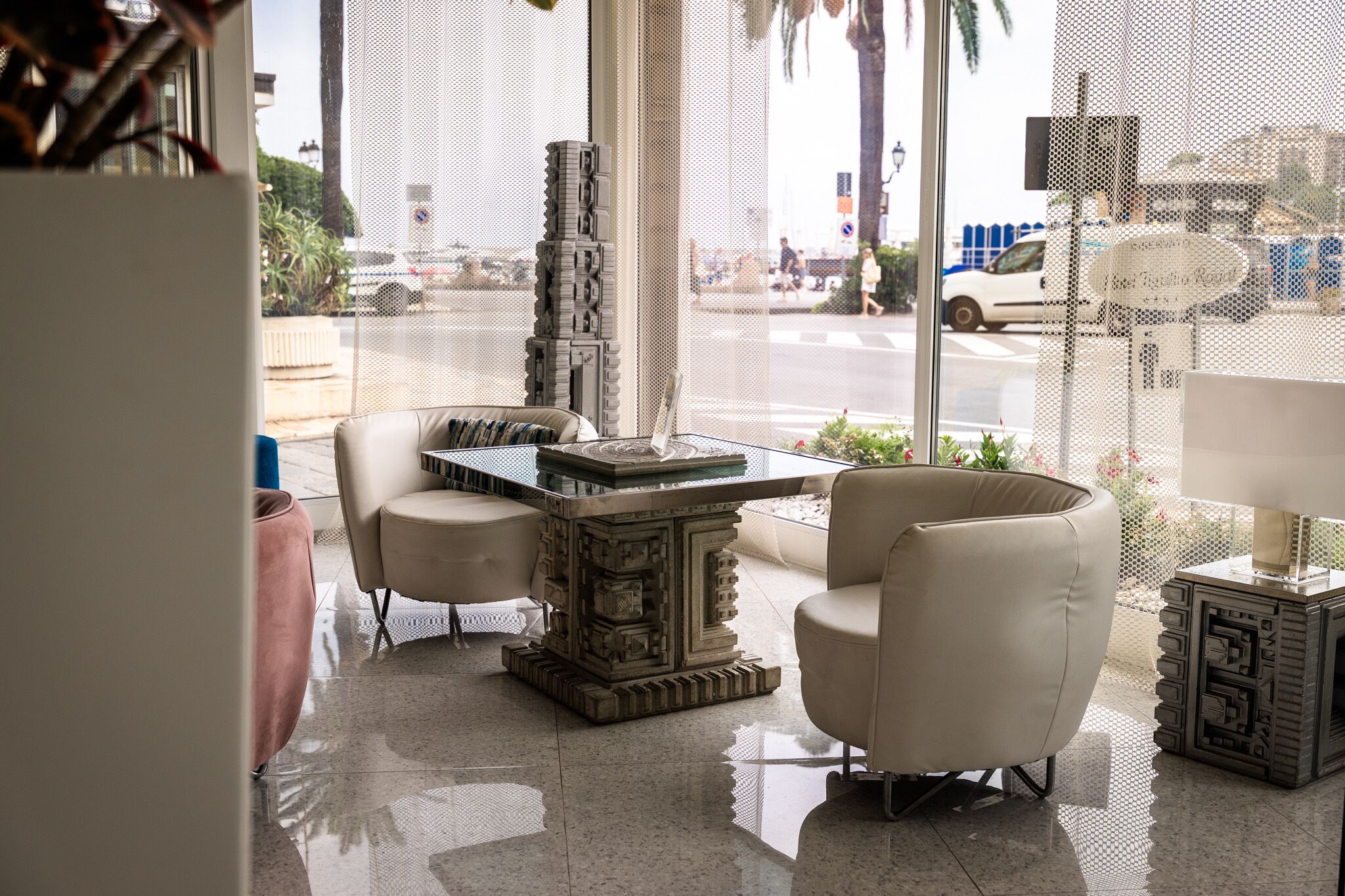A modern interior with a glass partition, a decorative table, and two white armchairs.