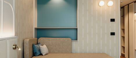 A modern room with a sofa, a wall-mounted light fixture, and a patterned wallpaper.