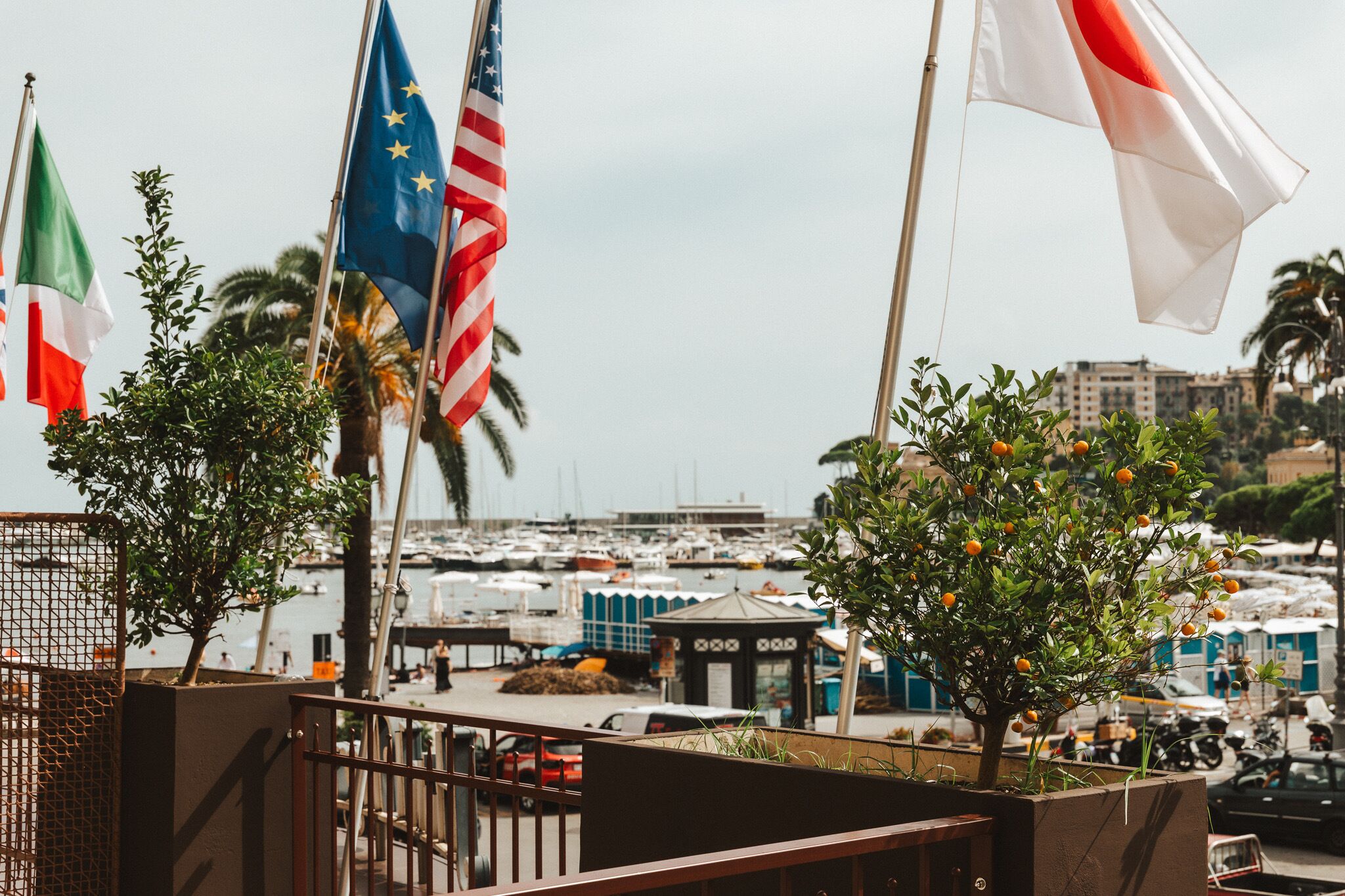 Un port de plaisance où flottent de nombreux pavillons, dont le drapeau italien, et qui offre une vue sur le paysage urbain en arrière-plan.