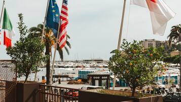 Un port de plaisance où flottent de nombreux pavillons, dont le drapeau italien, et qui offre une vue sur le paysage urbain en arrière-plan.