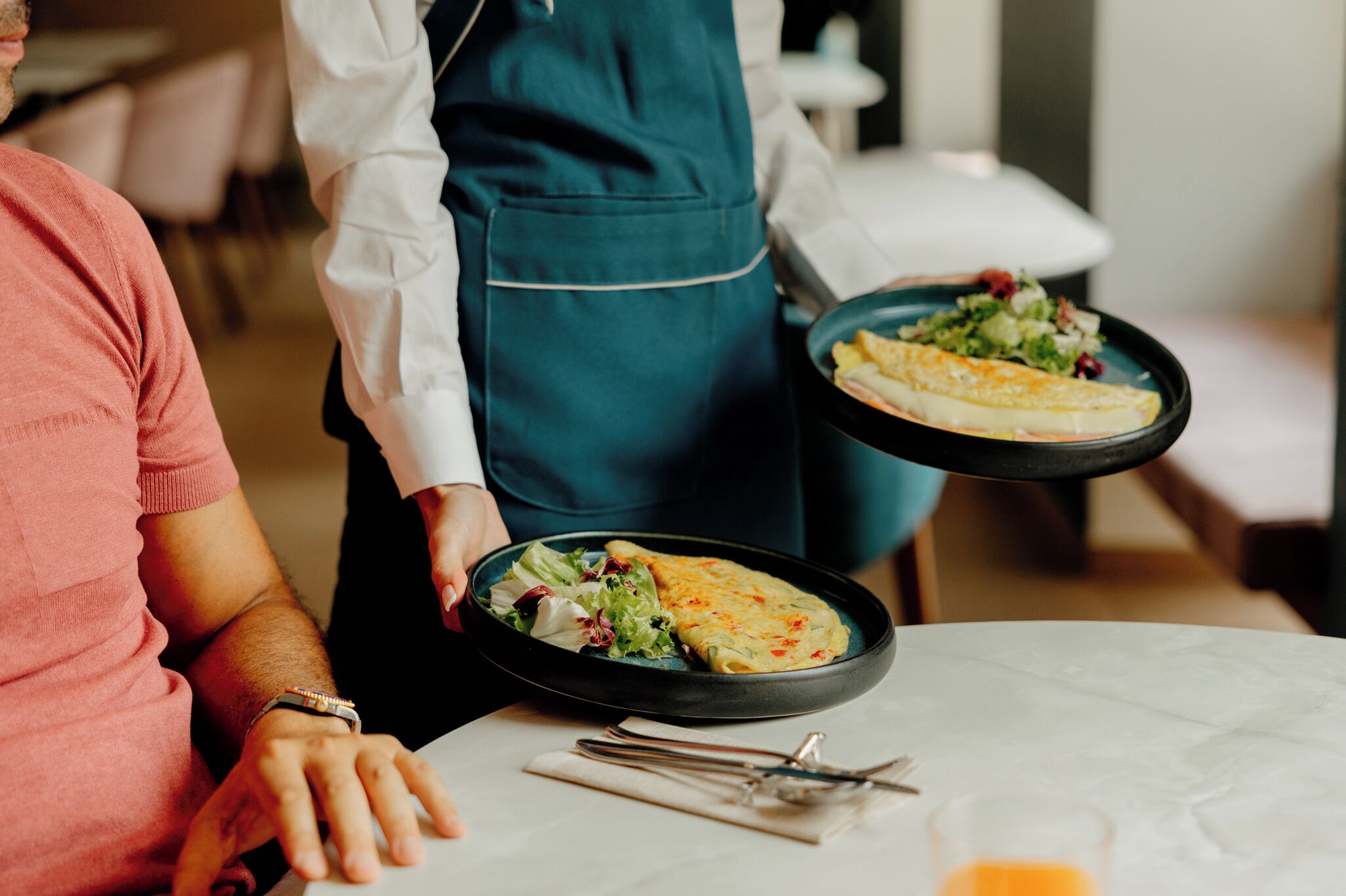 Una persona serve un pasto con un piatto di cibo e un'insalata su un tavolo.