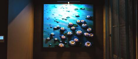 A wall-mounted artwork of water lilies and lotus flowers.