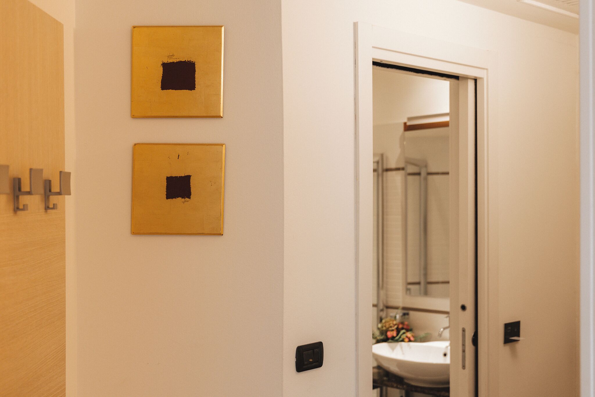 A bathroom with a sink, mirror, and two framed pictures on the wall.