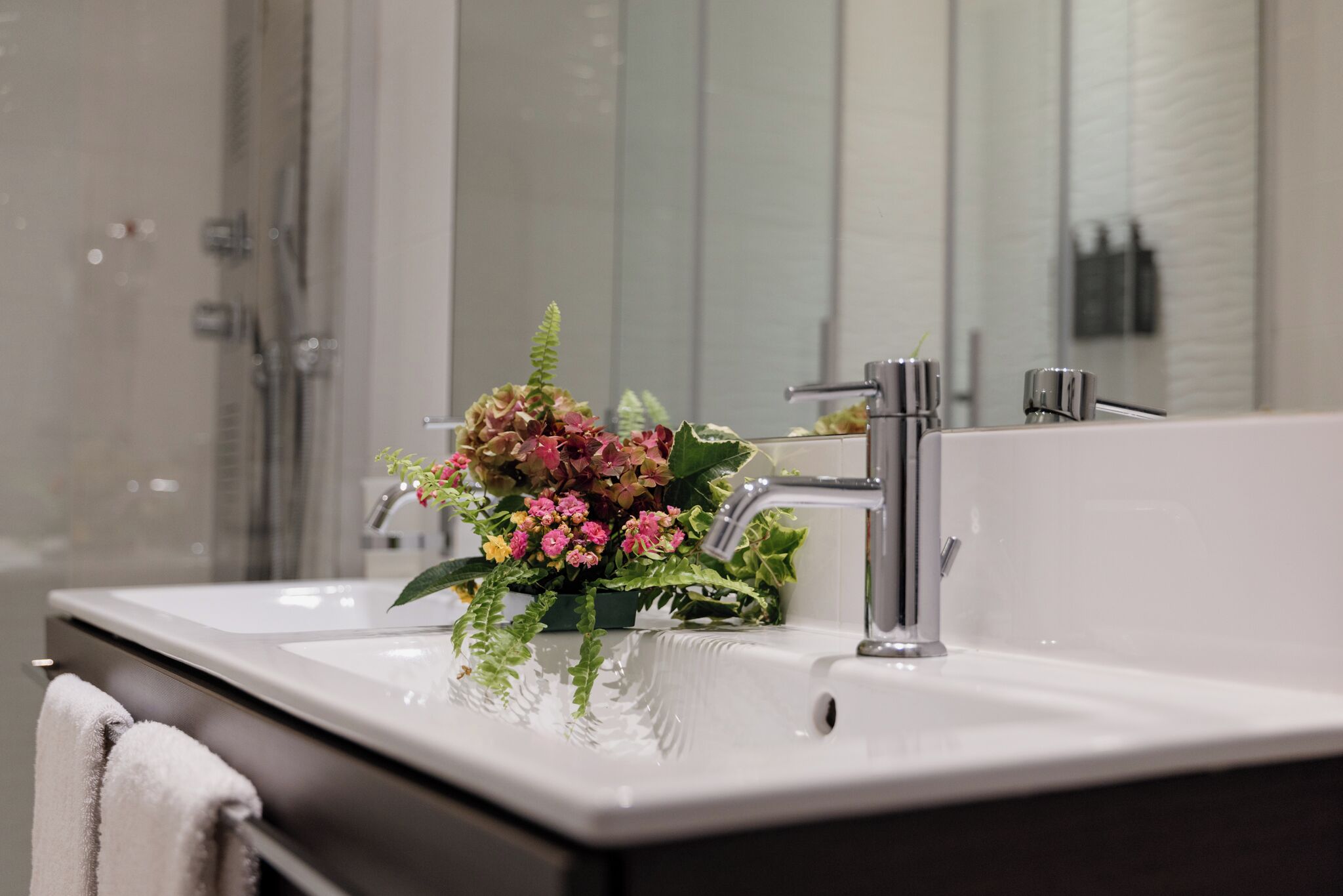 A bathroom with a white sink, a mirror, and a shower area.