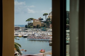 A marina with boats docked, a beach with people, and buildings in the background. - Best Western Plus Tigullio Royal Hotel (Rapallo)