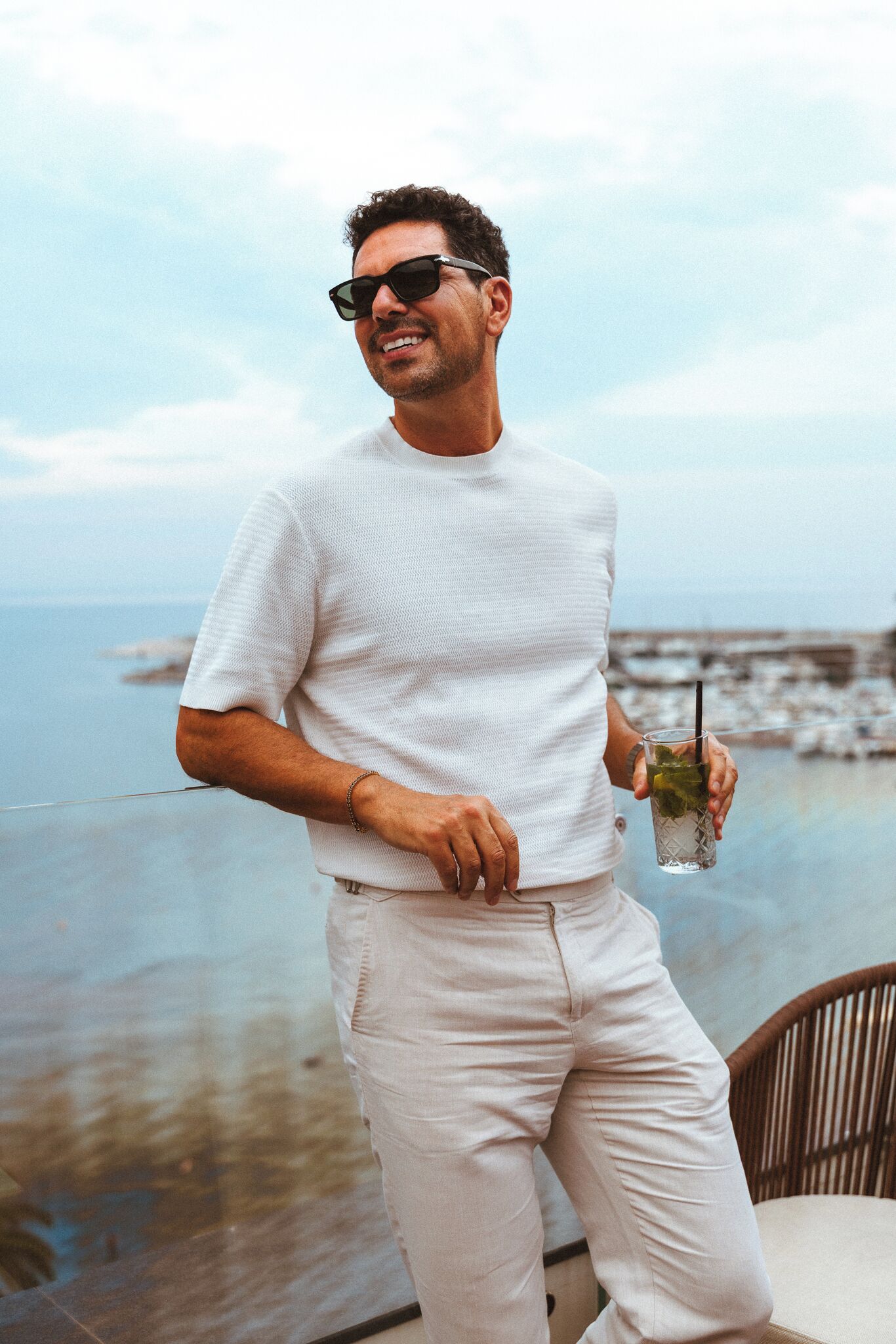 A person standing by a seaside with a drink in hand, overlooking the ocean.