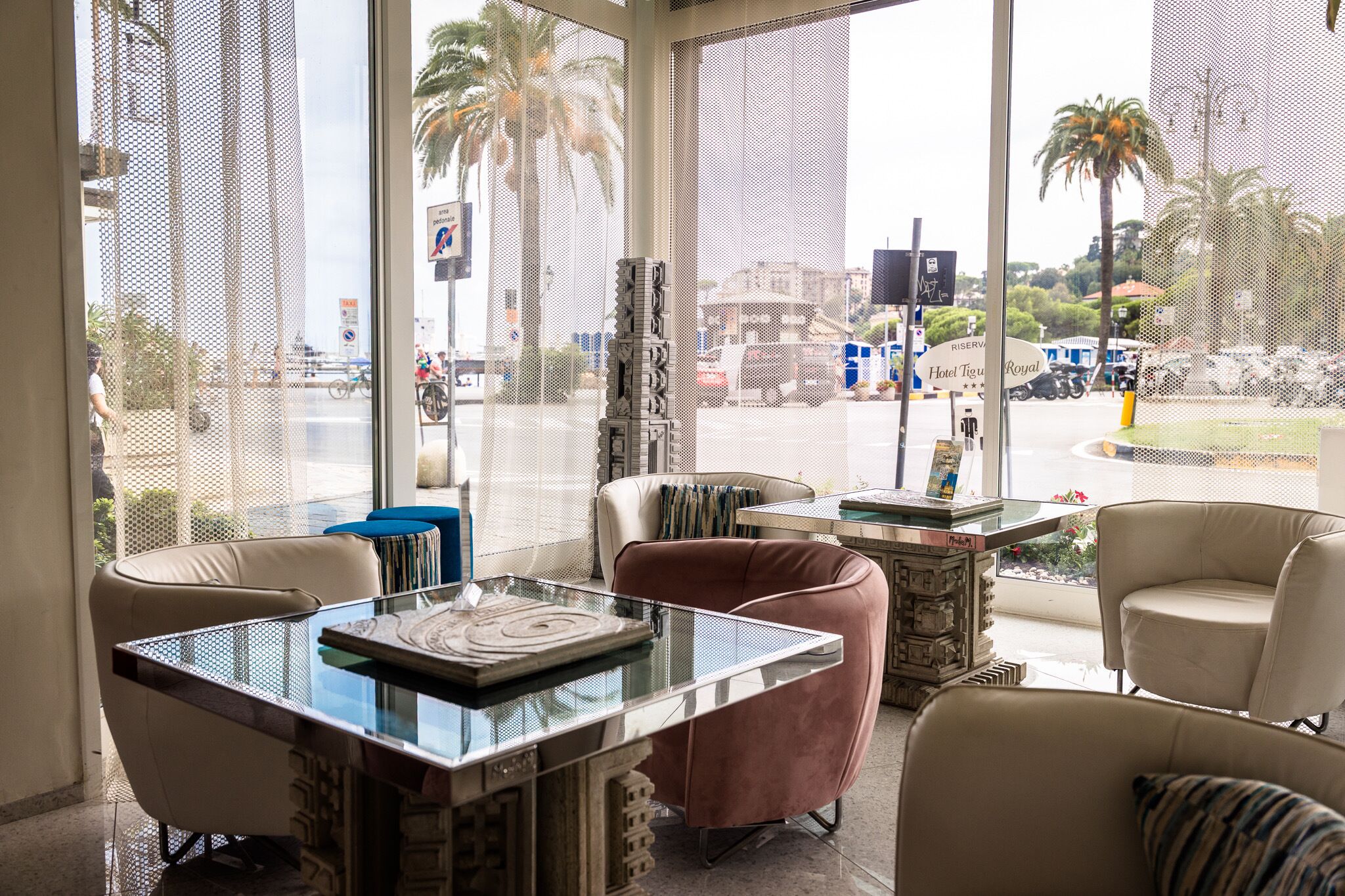 A room with a glass table, two chairs, a decorative pillar, and a view of the street outside.