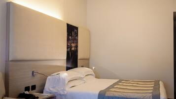 Una camera d'albergo con un letto, un comodino, una lampada e un quadro appeso al muro.