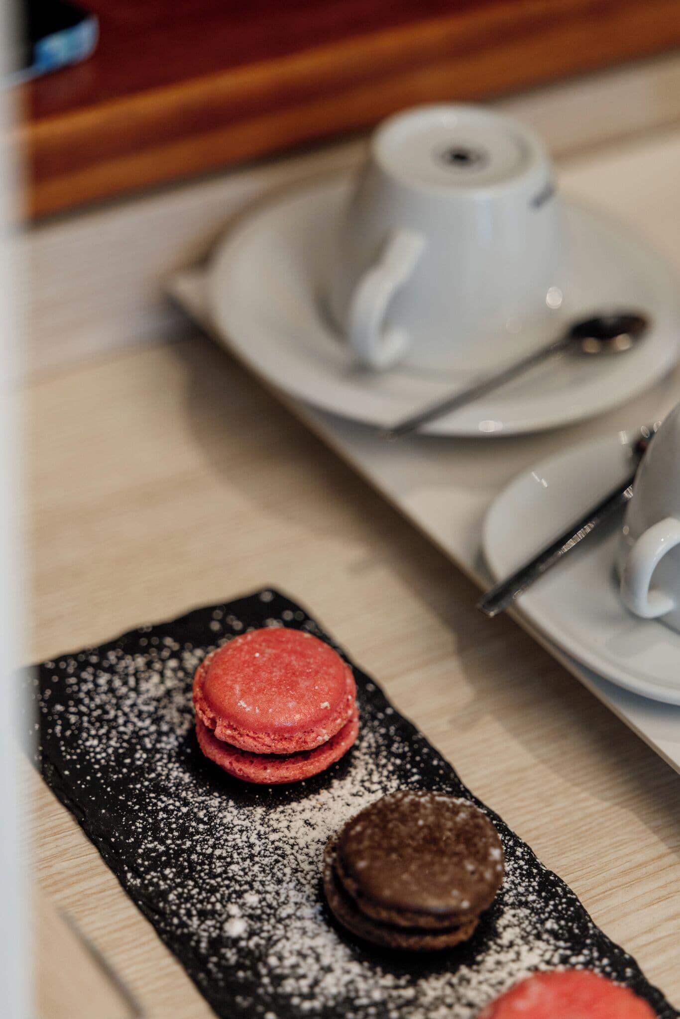 Een nagerechtbord met macarons en een kop thee op een tafel.