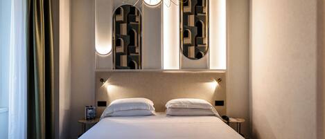 Ein modernes Hotelzimmer mit einem großen Bett, einem Nachttisch, einer Wandleuchte und einem geometrischen Wandmuster.