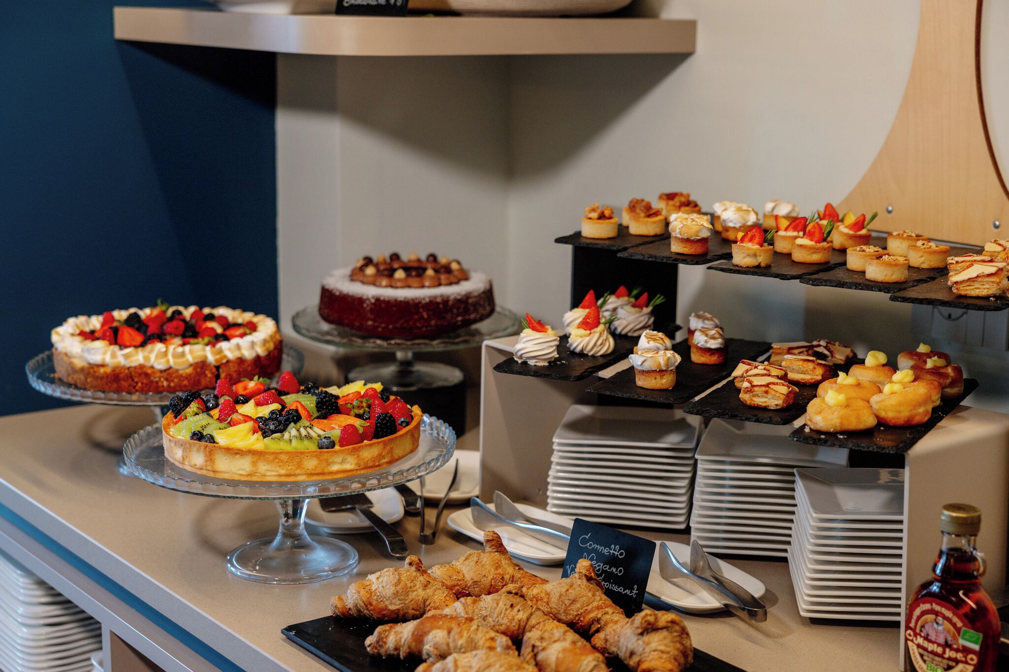 A buffet with various desserts and pastries, including cakes, fruit tarts, and pastries.