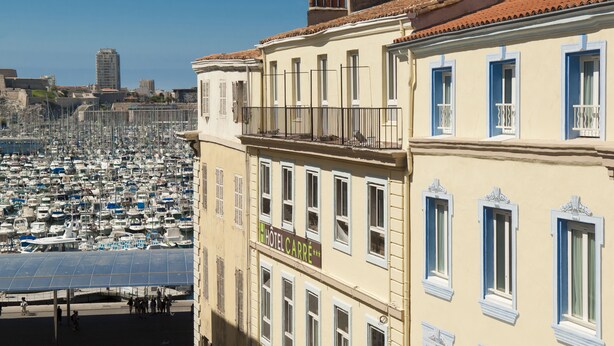 A hotel with a balcony overlooking a marina filled with boats.