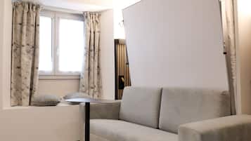 A modern living room with a sofa, a small side table, and a window with curtains.